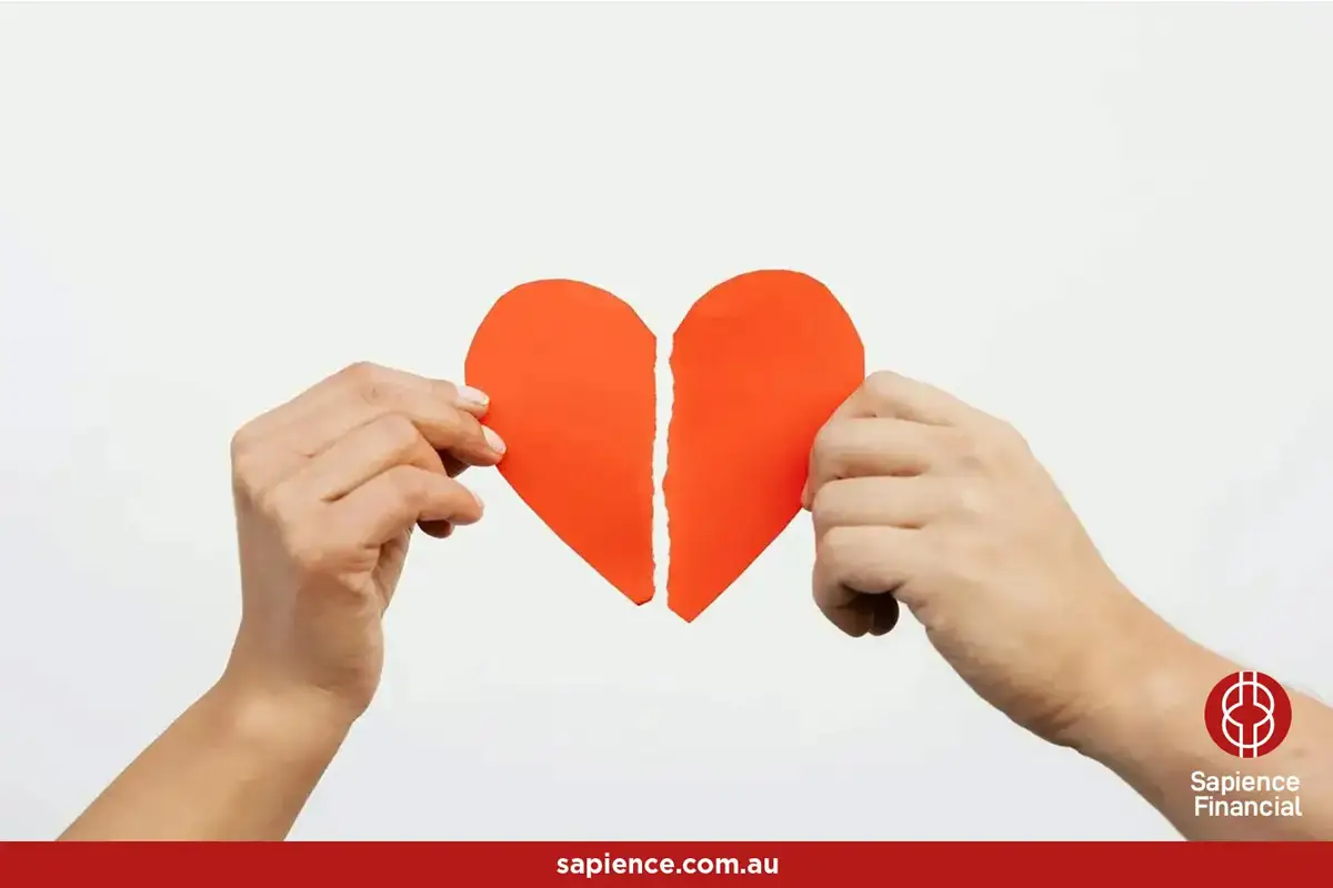 a red paper shaped heart being torn in two by separate hands
