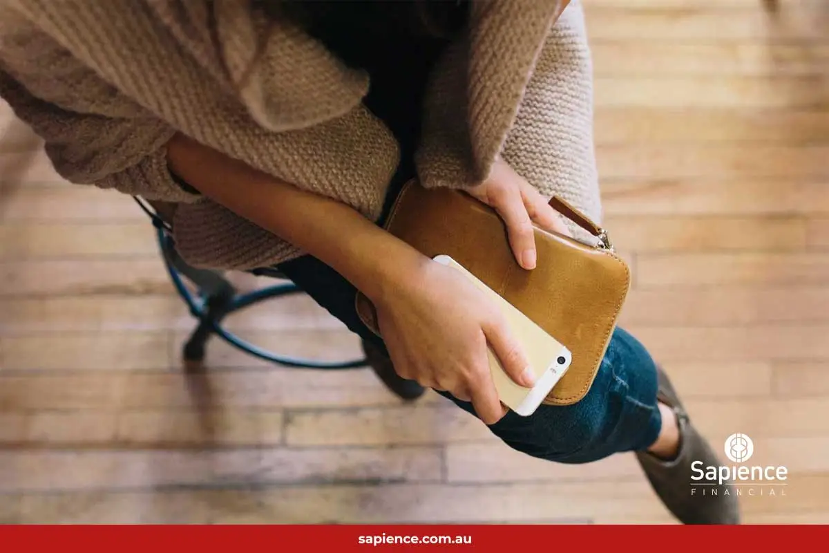 lady holding phone and purse sitting on stool