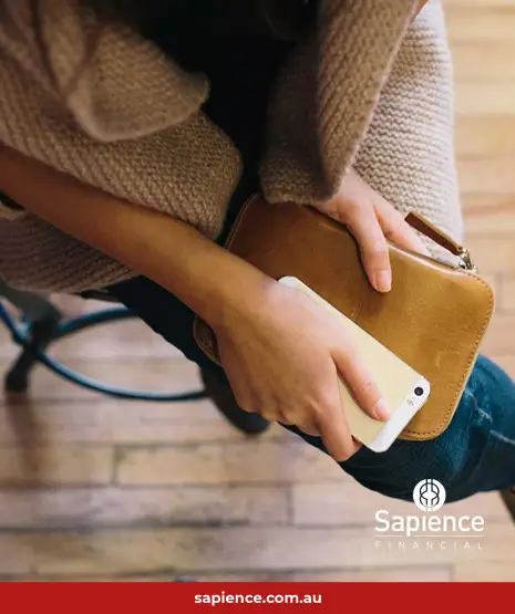 lady holding phone and purse sitting on stool