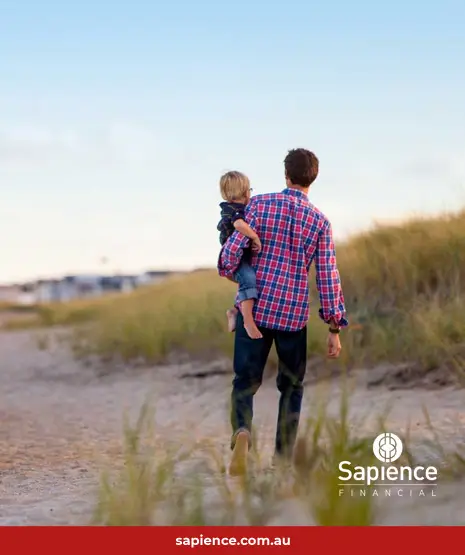 father walking on beach with child on his hip