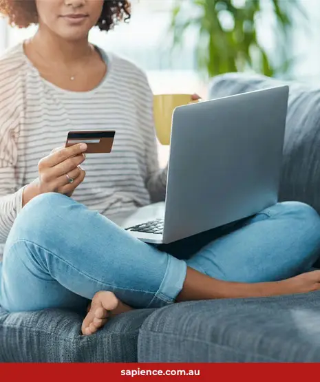 young women sitting on the cough paying bills by credit card